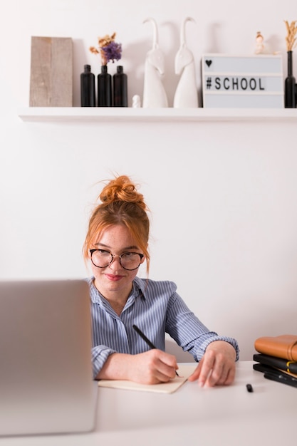 Vista frontal de uma professora sorridente em casa durante uma aula online