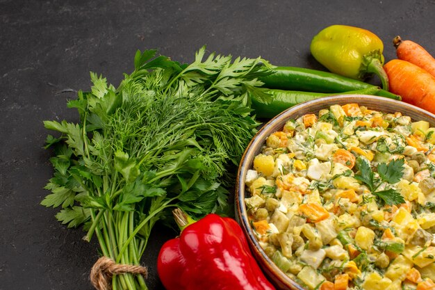 Vista frontal de uma saborosa salada com verduras e legumes na superfície escura