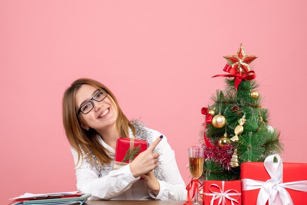 Vista frontal de uma trabalhadora sentada com presentes de Natal na rosa