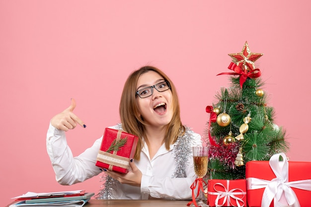 Vista frontal de uma trabalhadora sentada com presentes de natal na rosa