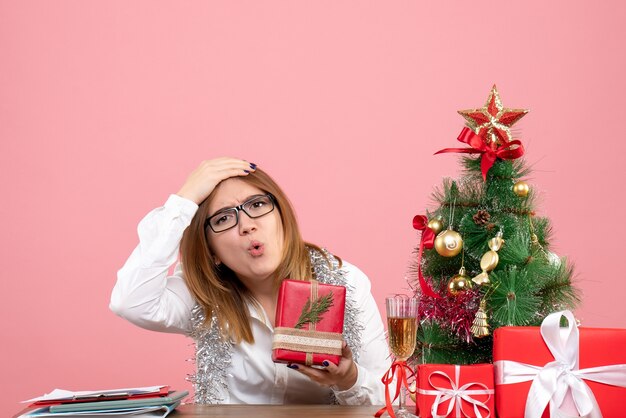 Vista frontal de uma trabalhadora sentada com presentes de Natal na rosa