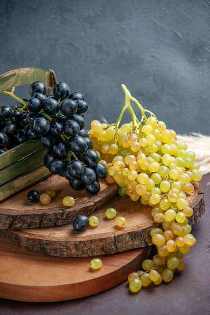 Vista frontal de uvas frescas maduras frutas escuras e verdes na superfície escura uvas para vinho fruta madura planta de árvore fresca