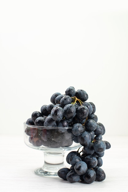 Vista frontal de uvas pretas frescas na superfície branca suco fresco maduro