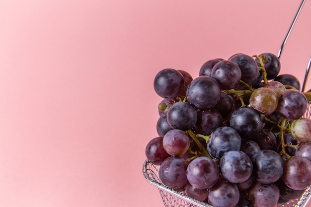 Vista frontal de uvas verdes frescas dentro da fritadeira na parede rosa