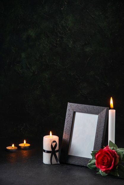 Vista frontal de velas acesas com flor vermelha na superfície escura