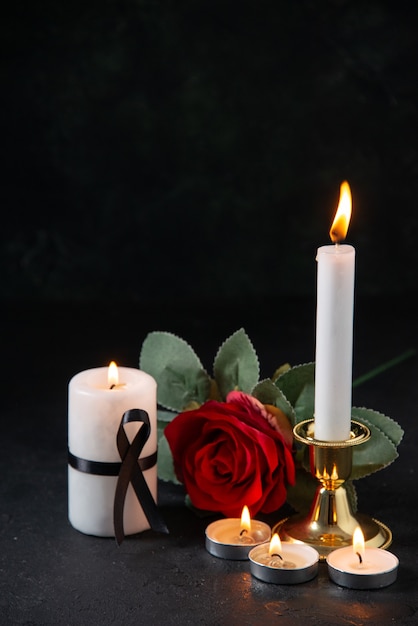 Foto grátis vista frontal de velas acesas com flor vermelha na superfície escura