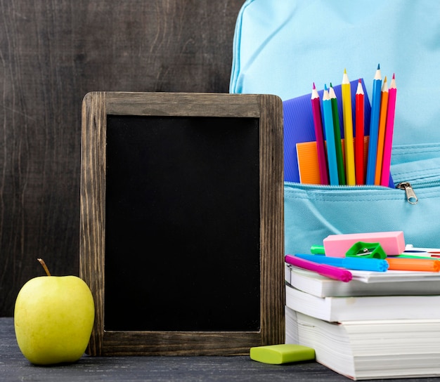 Vista frontal de volta aos artigos de papelaria da escola com maçã e quadro-negro