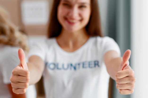 Vista frontal de voluntária desfocada fazendo sinal de positivo