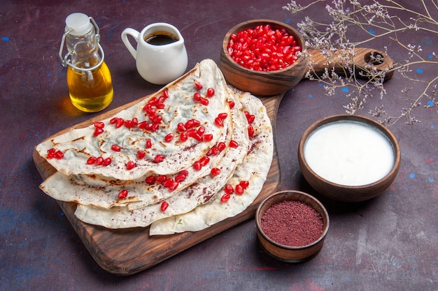 Vista frontal deliciosa carne qutabs pitas com romãs vermelhas frescas em uma superfície roxa escura com massa refeição pita comida