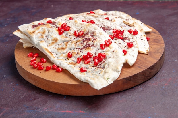 Vista frontal deliciosa carne qutabs pitas com romãs vermelhas frescas na mesa roxa-escura farinha de massa de pão pita