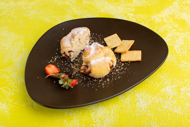Vista frontal deliciosa massa dentro do prato com biscoitos na mesa amarela