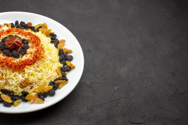 Vista frontal deliciosa plov com óleo e passas dentro de um prato no espaço escuro