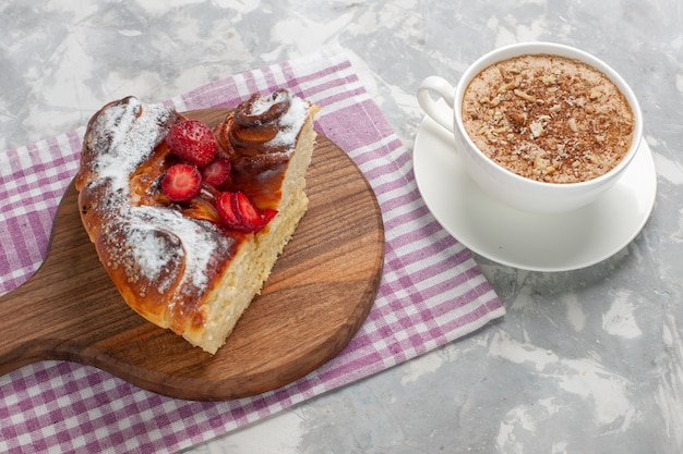 Vista frontal deliciosa torta de morango assada e saborosa fatia de sobremesa com uma xícara de café na mesa branca