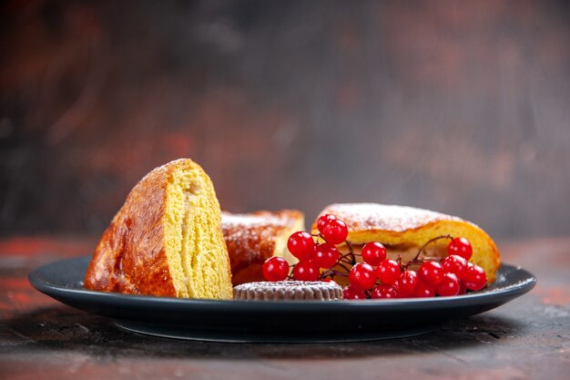 Vista frontal deliciosa torta fatiada com frutas vermelhas na mesa escura