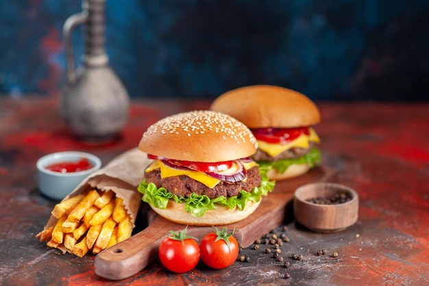 Vista frontal deliciosas batatas fritas com cheeseburgers em fundo escuro lanche sanduíche fast-food torrada hambúrgueres jantar