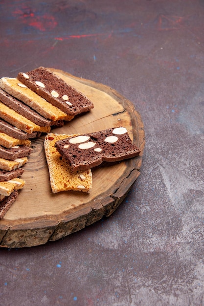 Vista frontal deliciosas fatias de bolo com nozes em uma mesa escura chá açúcar cookies biscoito torta doce