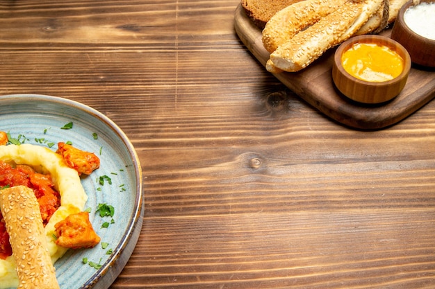 Vista frontal deliciosas fatias de frango com purê de batata e pão na mesa de madeira refeição de batata comida pimenta picante