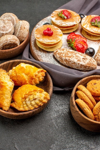 Vista frontal deliciosas panquecas com frutas e bolos doces em superfície escura bolo sobremesa doce