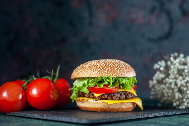 vista frontal delicioso hambúrguer de carne com tomate vermelho em fundo escuro