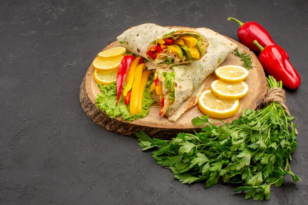 Vista frontal - delicioso sanduíche de frango em fatias de shaurma com limão e verduras no espaço escuro