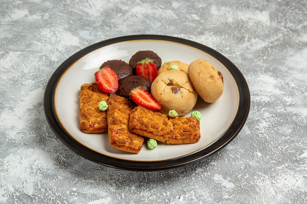 Vista frontal deliciosos bolos com biscoitos e morangos na superfície branca biscoito bolo de açúcar torta doce chá biscoito