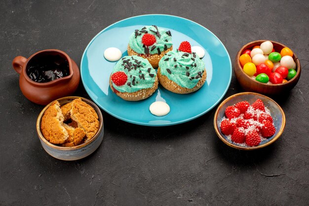 Vista frontal deliciosos bolos cremosos com doces em um fundo cinza escuro doce biscoito bolo sobremesa cookies cor