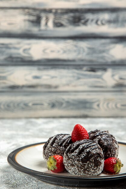 Vista frontal deliciosos bolos de chocolate com morangos vermelhos em uma parede branca clara de chocolate açúcar biscoito bolo doce assar biscoitos
