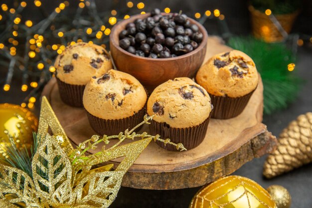 Vista frontal deliciosos bolos de frutas em torno de brinquedos de árvore de férias em fundo escuro bolo de sobremesa doce foto creme