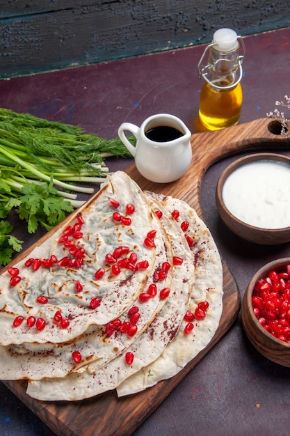 Vista frontal deliciosos qutabs pitas com carne moída dentro e com romãs frescas em massa de superfície escura com farinha de carne de pita