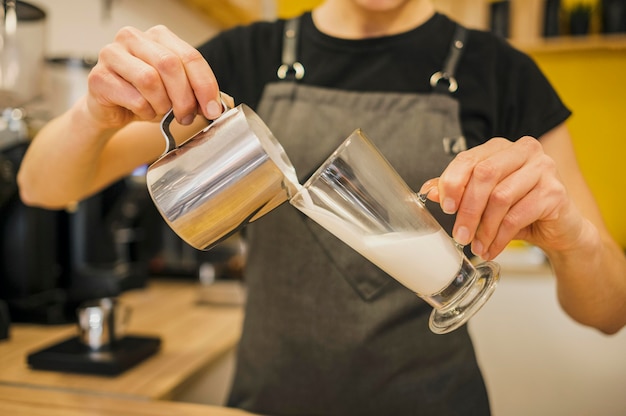 Vista frontal do barista derramando leite