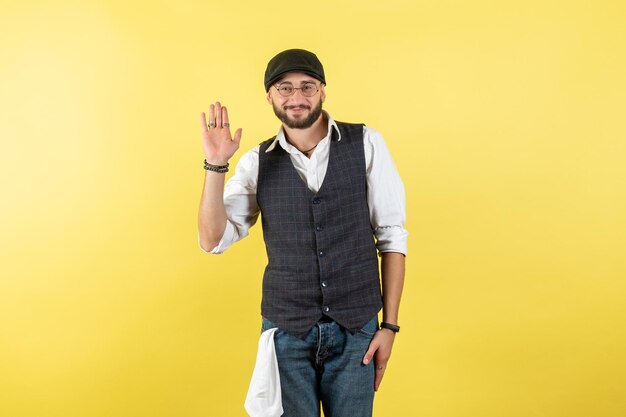 Vista frontal do barman masculino sorrindo e cumprimentando na parede amarela trabalho de bebida do clube masculino noite modelo trabalho