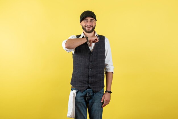 Vista frontal do barman masculino sorrindo e parado na parede amarela modelo noturno bebida trabalho clube trabalho masculino