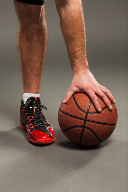 Vista frontal do basquete pressionado pelo jogador do sexo masculino