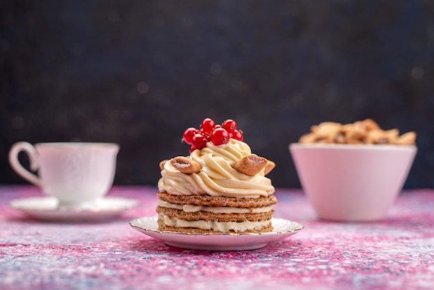 Vista frontal do bolo de creme com cranberries xícara de café e travesseiros biscoitos na superfície escura