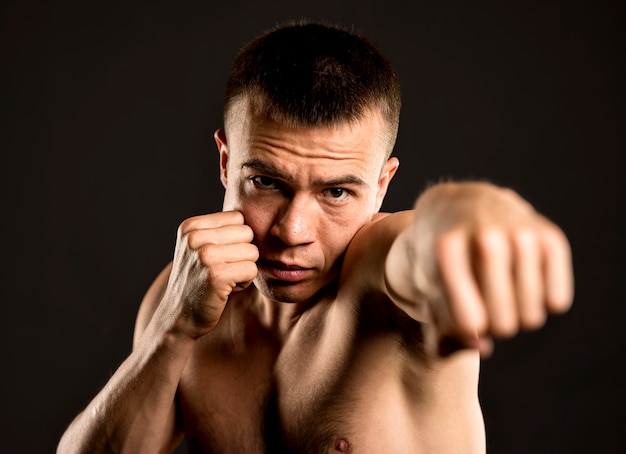 Vista frontal do boxer masculino posando com posição de boxe