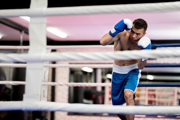 Vista frontal do boxer masculino praticando no ringue