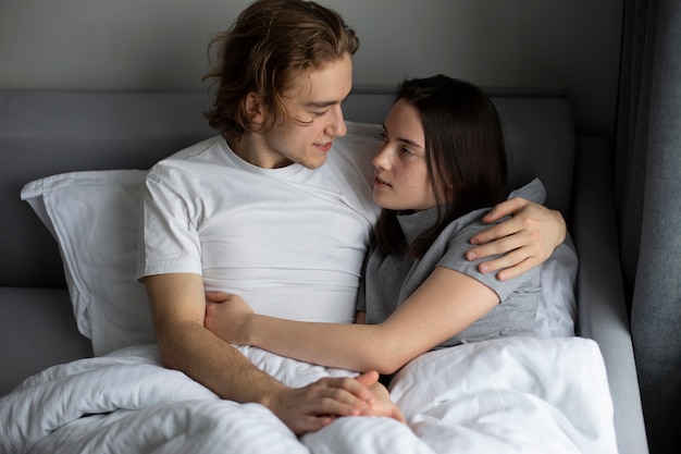 Vista frontal do casal abraçando na cama