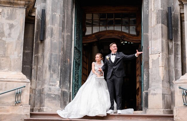Vista frontal do casal alegre vestindo roupas de casamento da moda saindo do antigo