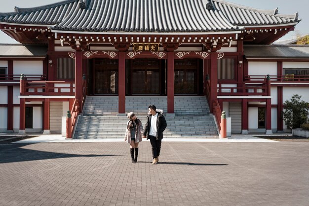 Vista frontal do casal em frente ao prédio japonês