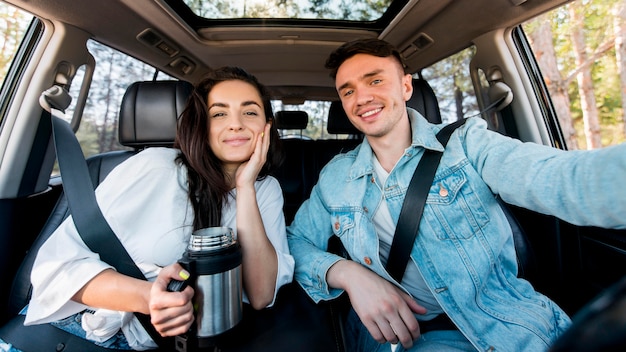 Vista frontal do casal tirando uma selfie no carro