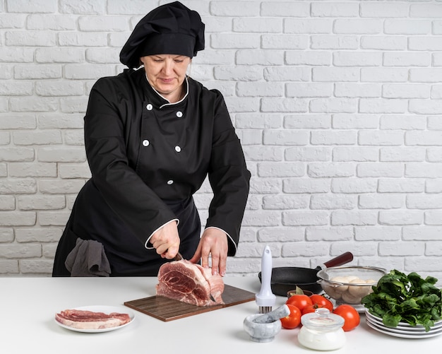 Vista frontal do chef feminino cortar carne
