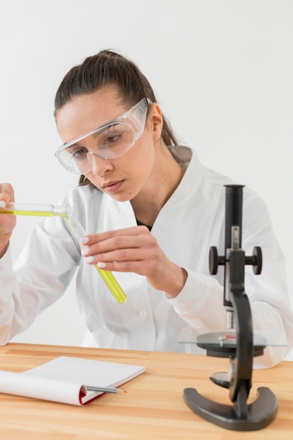 Foto grátis vista frontal do cientista feminina analisando poções em tubos