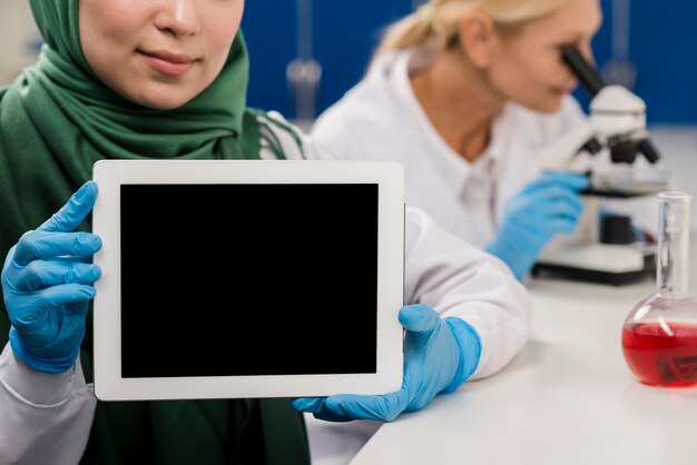 Vista frontal do cientista feminina segurando o tablet no laboratório
