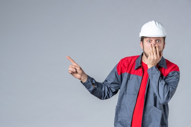 vista frontal do construtor masculino de uniforme e capacete em fundo cinza