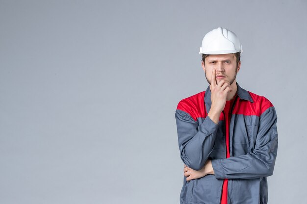 vista frontal do construtor masculino de uniforme e capacete em fundo cinza