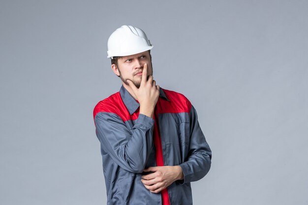 Vista frontal do construtor masculino de uniforme e capacete em fundo cinza