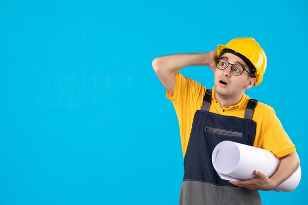 Vista frontal do construtor masculino em uniforme amarelo com plano em azul