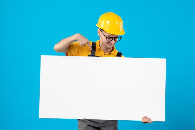 Vista frontal do construtor masculino em uniforme amarelo com plano em azul