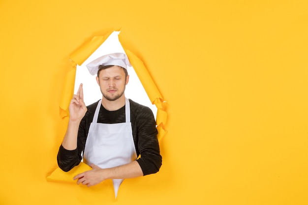 Vista frontal do cozinheiro masculino com capa branca e boné amarelo rasgado foto cor branca cozinha comida homem cozinha