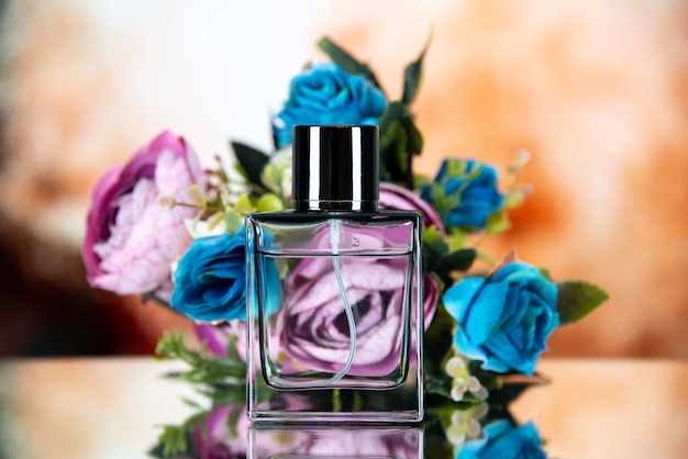 Vista frontal do frasco de perfume com flores coloridas sobre fundo bege desfocado